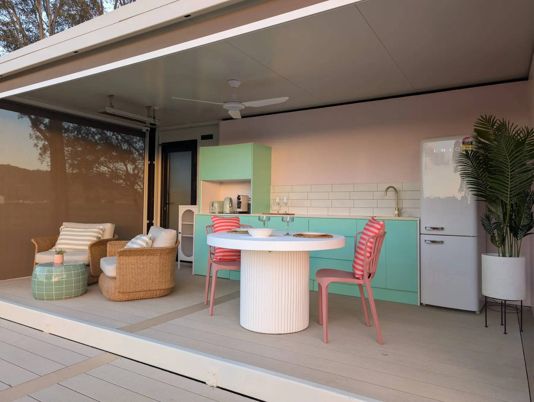 The pavilion open to the deck: mint kitchen, round dining table and lounge chairs