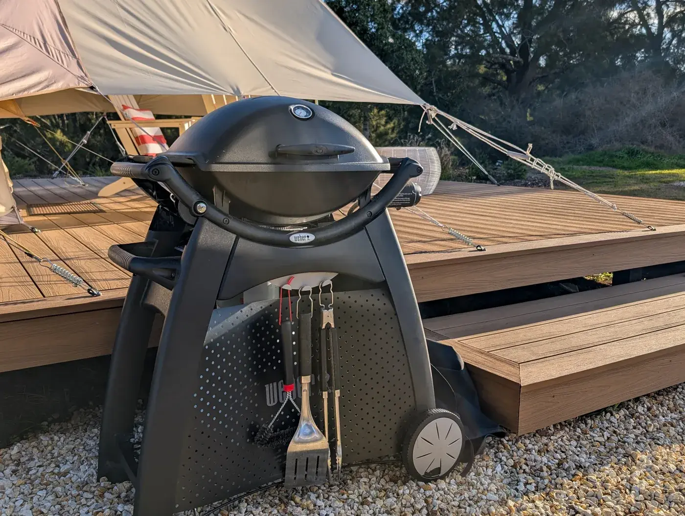 The Weber beside the deck with tools hanging under the hood