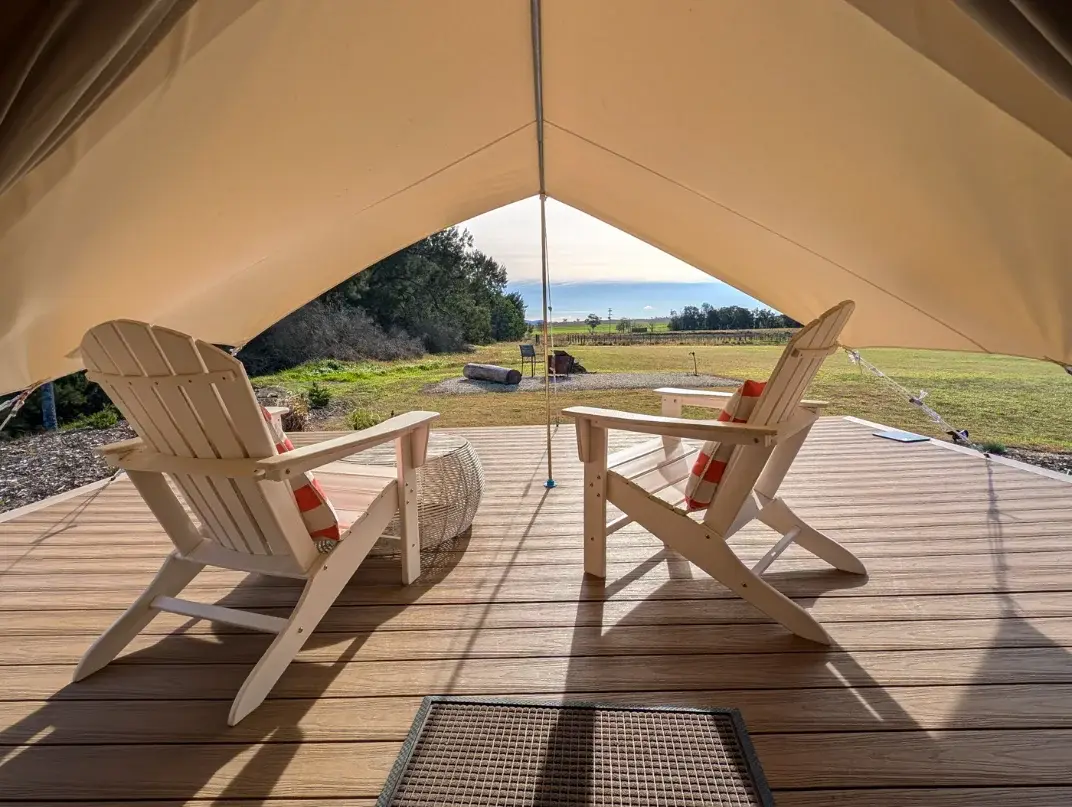 The view from inside the Bell Tent across its deck to the firepit in the paddock beyond