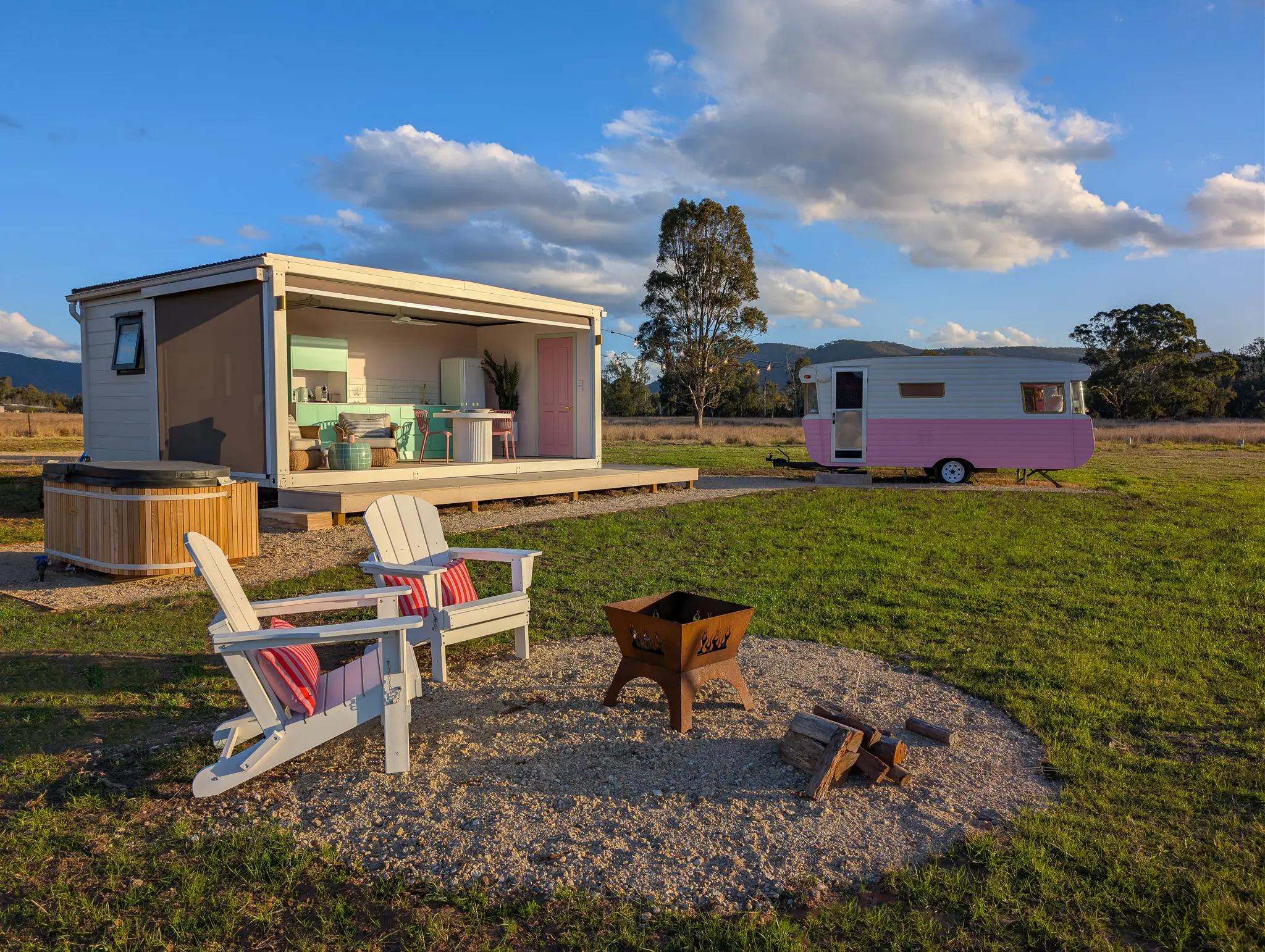The Caravan at Broke Estate: the pink vintage van, the open pavilion with its mint kitchen, and two chairs around the firepit in the paddock